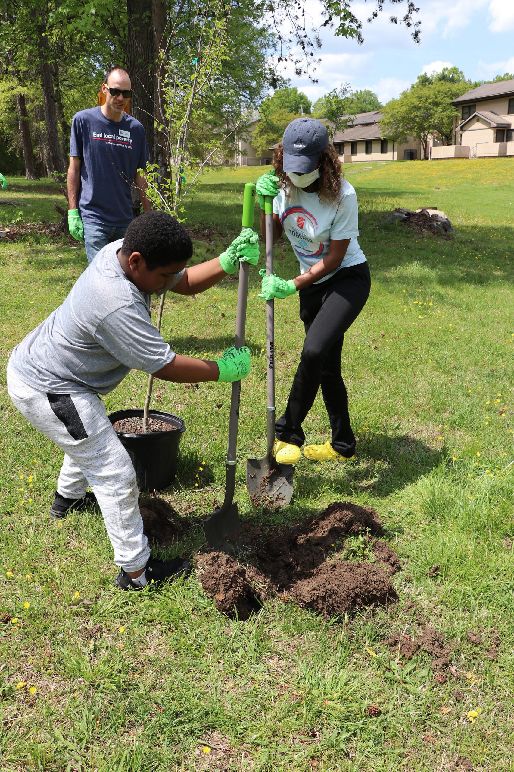 A young child and an adult planting trees together, symbolizing generational collaboration and the legacy of giving back to the community.