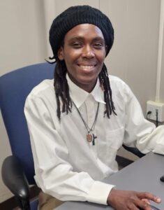 Sandra smiling while sitting at a computer, representing her journey to stability and the skills she gained through the Family Success Center.